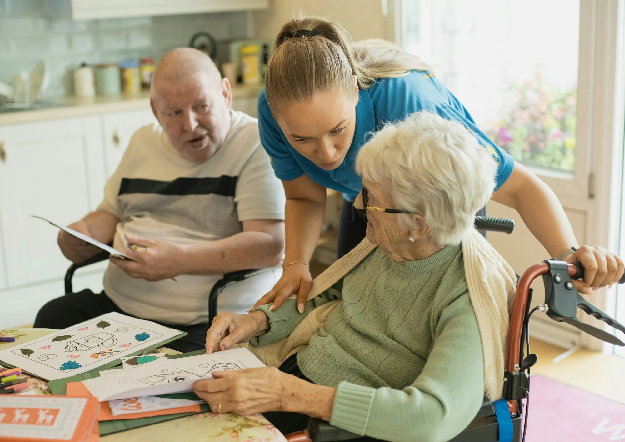 A caregiver sitting with an older couple at a table, working through an activity together